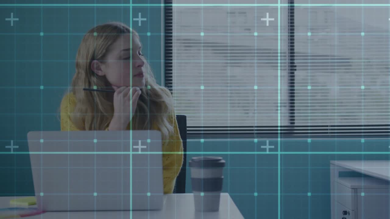 Office worker typing on laptop and spawning gridlines before jotting planning notes on sticky notes