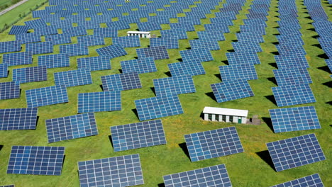 a vast solar farm with numerous panels on green fields under a clear blue sky