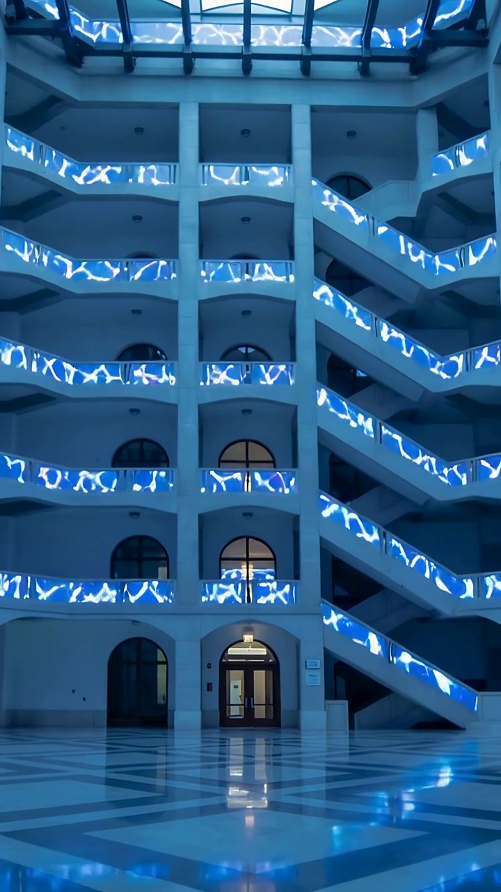 Vídeo vertical: Pulsos de LED começando a percorrer os corrimãos da varanda no átrio, projetando reflexos