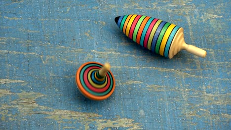 two wooden colorful top spin whirligig on old blue plywood background