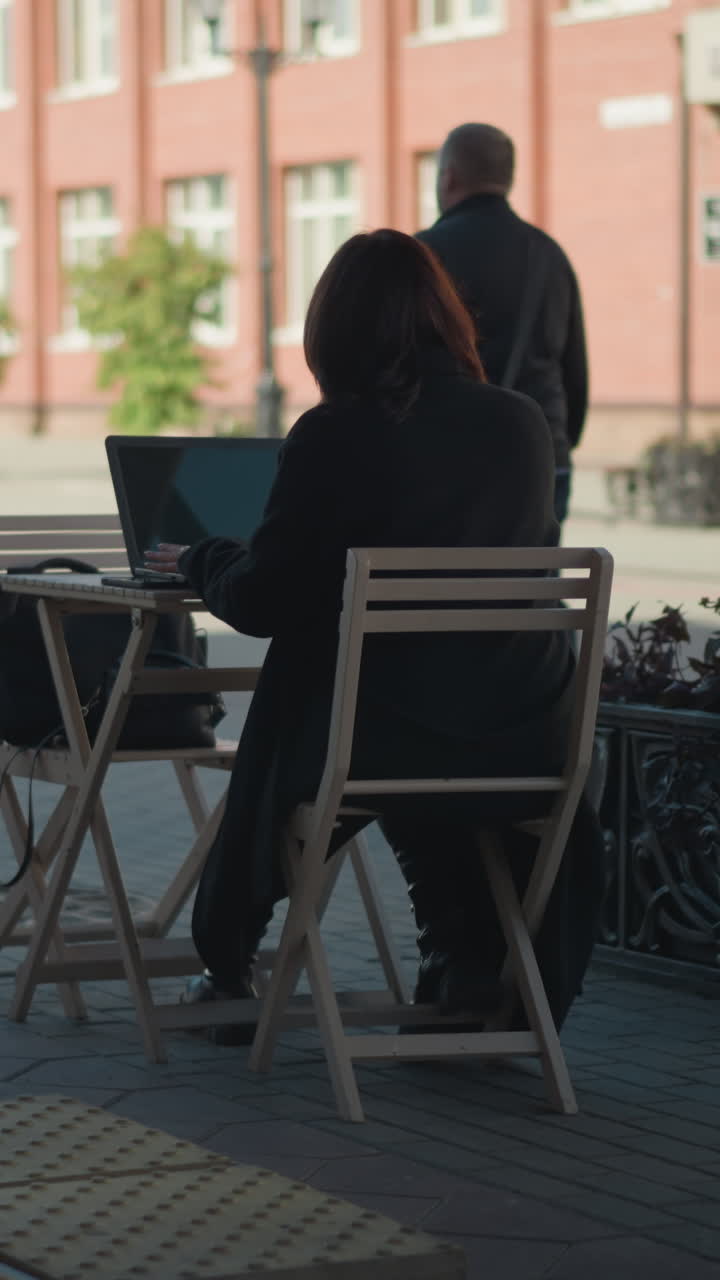 나무 의자, 비 식물, 도시 거리 풍경으로 둘러싸인 카페에서 노트북으로 야외에서 일하는 프리랜서, 빛 아래 배경에서 는 사람