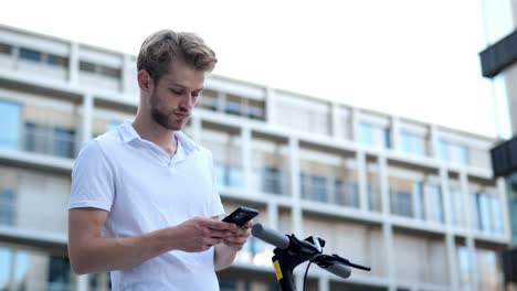 Young-businessman-activating-an-e-scooter-with-his-phone,-medium-shot