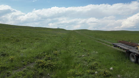 camión semi estacionado en el medio de un hermoso valle de hierba verde rodeado de montañas