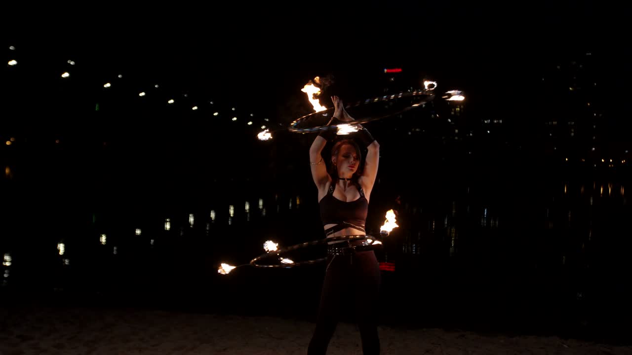 빨간 머리 불 소녀는 저녁에 불 울타리를 휘두르고 있습니다.