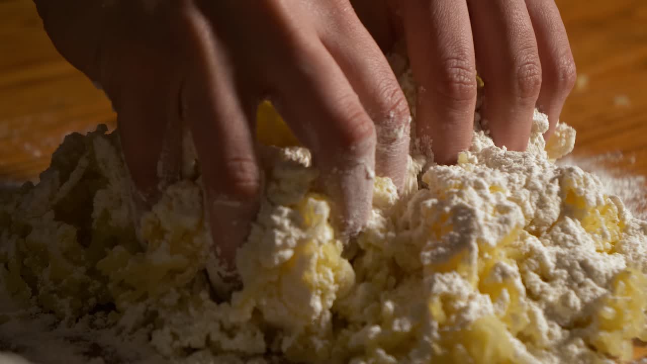 4K close up slow motion shot raw gnocchi dough kneaded by hand on a wooden table with white flour on top