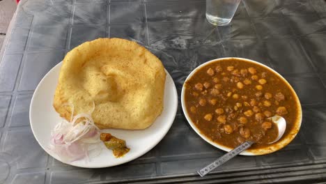 górne ujęcie indyjskiej kuchni śniadaniowej chole bhature lub poori z curry z ciecierzycy chana masala, podawane z mieszanką marynat i pokrojoną cebulą