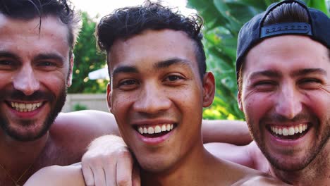 retrato de tres amigos masculinos al aire libre relajándose en la piscina y disfrutando de la fiesta de la piscina de verano