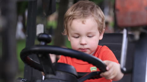 kid turns wheel of the tractor