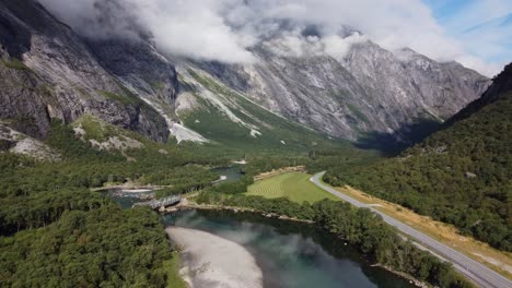 aerial footage showing the rauma river in norway, with mountains, greenery and grass