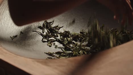 las manos de las mujeres asiáticas revuelven las hojas de té verde en la sartén tradicional