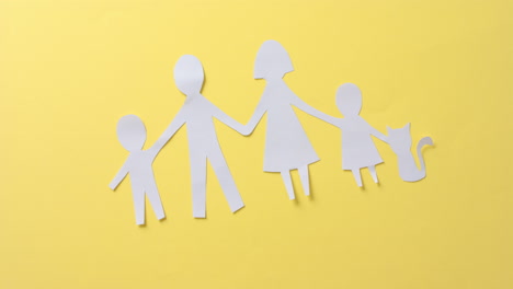 close up of family with cat made of white paper on yellow background with copy space