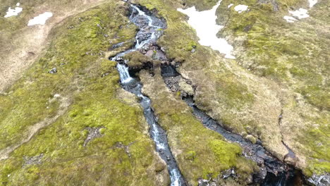 Drohnenschuss,-Der-Sich-Von-Kleinen-Isländischen-Wasserfällen-Auf-Einem-Hügel-Vorwärts-Bewegt