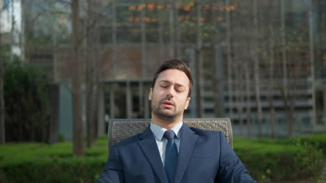 overworked man in 30th in formal suit feeling tired working with documents sitting at city park