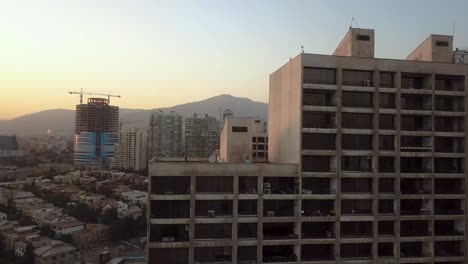 tehran iran drone shot move up rising shot big building in city golden time in sunset clear sky and mountain in landscape people live in tower apartment air pollution risk concept city life quality
