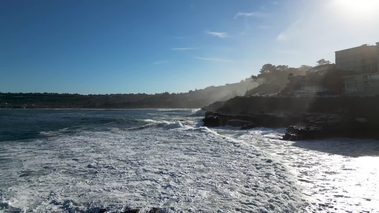 imágenes en 4k de grandes olas oceánicas chocando contra acantilados a marea alta en la bahía de la jolla en san diego, california, mientras un pelícano vuela en la toma.