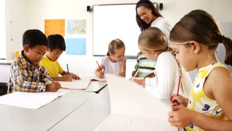 teacher assisting school kids with their classwork in classroom