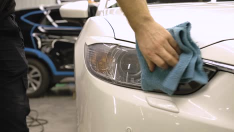 man covering car with vinyl polyurethane tape. films for the car. sticker protective film on the headlight of the car