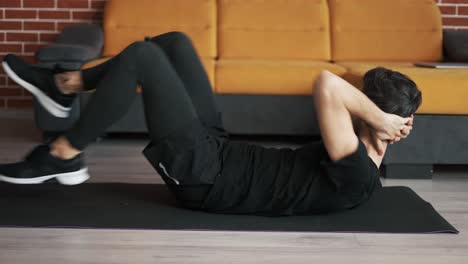 man training on mat at home, doing bicycle exercise on back, closeup