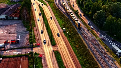 aerial over highway interchange with moving vehicles in daylight, cars boarder along side frontage road and train on tracks