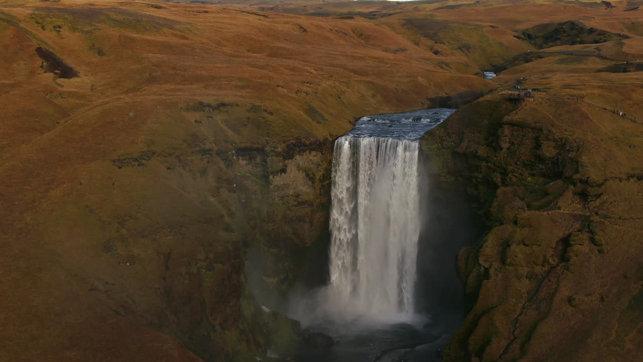 drone cinematográfico skogafoss cascada islandia pan hacia atrás revelan movimiento con pájaros, arco iris y luz del sol de la tarde