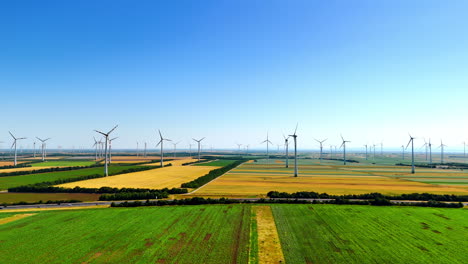 flying over the green field approaching the fields with wind farms. production of sustainable energy