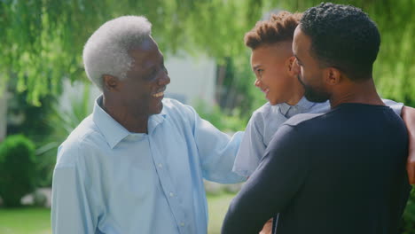 Familia-Masculina-Multigeneracional-Sonriente-En-Casa-En-El-Jardín-Juntos