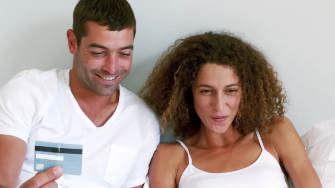 Casal fofo fazendo compras online na cama