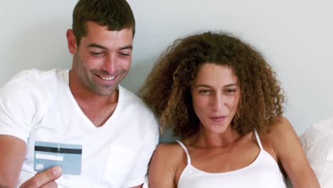pareja linda haciendo compras en línea en su cama