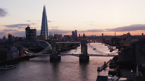 Slide-and-pan-footage-of-one-of-city-symbols.-Famous-Tower-Bridge-over-River-Thames-against-pink-sky-after-sunset.-Water-surface-reflecting-twilight-sky.-London,-UK