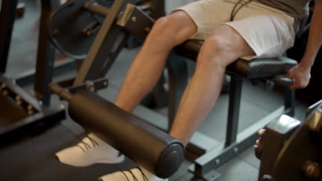 unknown bodybuilder making leg extension in sport club. legs training at gym