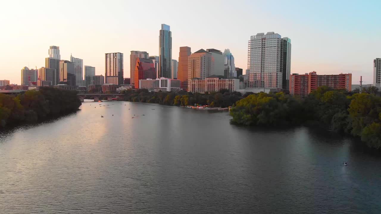 Tomada cinematográfica de Austin, Texas, com pessoas aproveitando o lago e um pássaro voando majestosamente pela tela