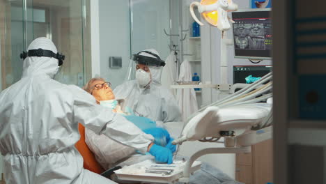 stomatologist in protective suit performing dental examination