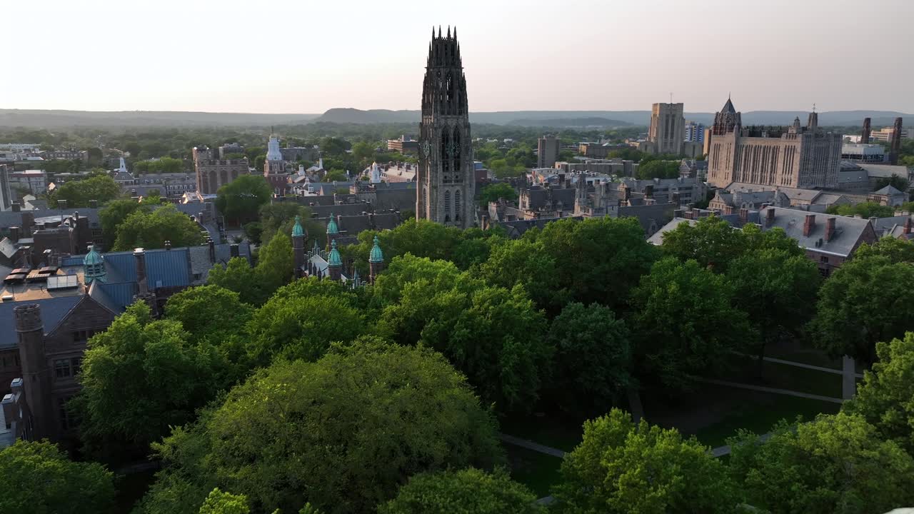 Brick buildings and harkness tower of Yale university campus in New Haven. Aerial flyover shot. Sunset time in American city of Connecticut. Wide shot
