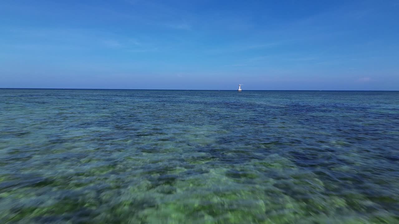 Fast drone movement skimming the surface of My Hoa Lagoon, highlighting the crystal clear turquoise waters under the noon sun.