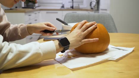 foto deslizante de una mujer tallando calabaza naranja en casa para halloween