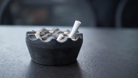 dirty ashtray with cigarette butts on a table