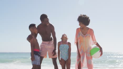 retrato de una familia afroamericana sonriente abrazándose en una playa soleada