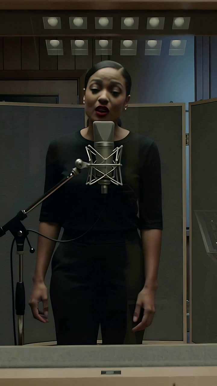 Video verticale: Cantante che inspira mentre registra una canzone in uno studio di registrazione all'interno di una cabina, indossando un abito nero