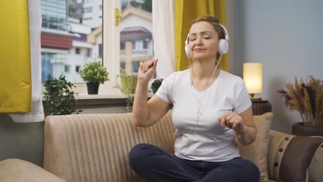 Woman-looking-out-the-window-and-listening-to-music-with-headphones.