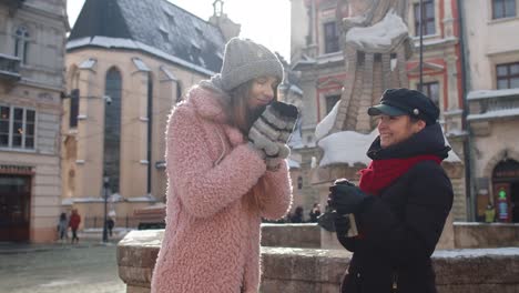 two women in winter clothes walking in a snowy city street