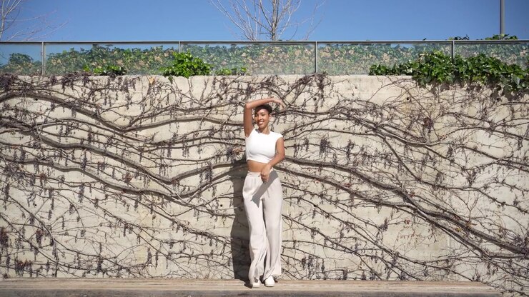 Una donna alla moda che posa con grazia contro un muro artistico in un ambiente esterno luminoso