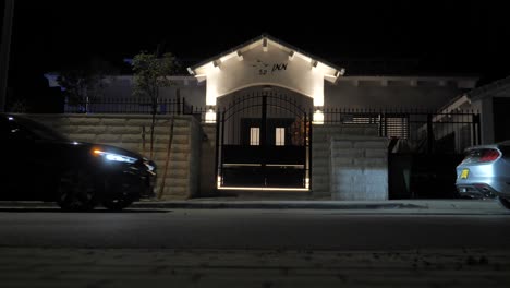 Coupe-car-drives-and-parks-on-street-in-front-of-illuminated-house-at-night