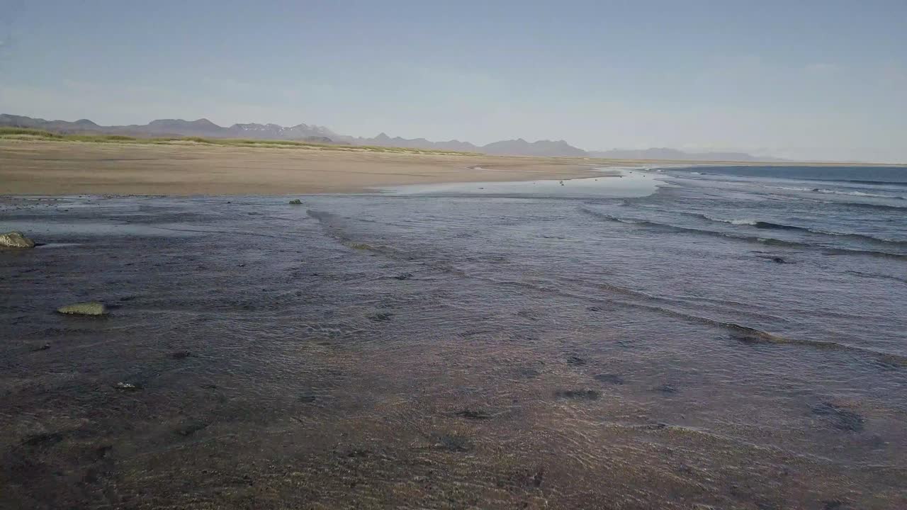 vuelo bajo sobre la rara playa de arena dorada y el océano durante el verano soleado en la península de snaefellsness, islandia
