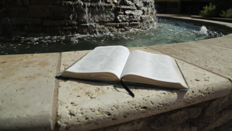 holy book by a peaceful water fountain background : pan up close