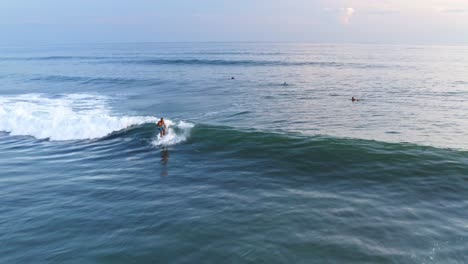 aerial: surfer catching perfect breaking wave and riding wave to shore
