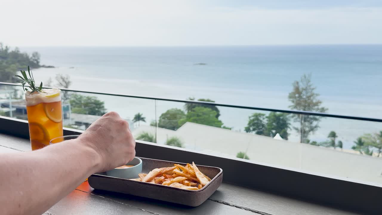 A serene moment enjoying fries and drinks with a stunning ocean view at a beachside bar in Phuket, Thailand