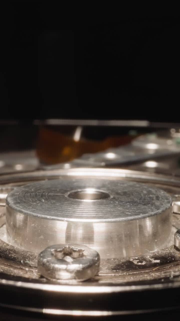 Open HDD with detailed mechanism reflecting bright studio light on dark background. Electro-mechanical data storage device for computers macro