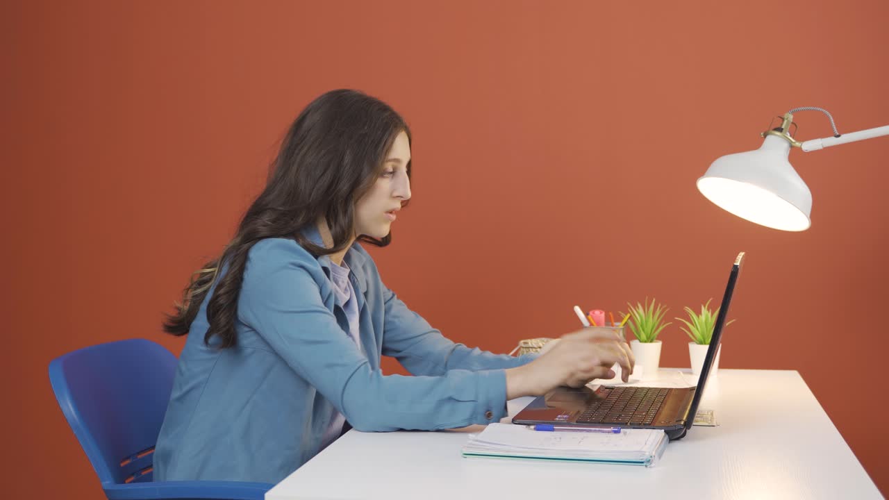 mujer joven mirando la computadora portátil haciendo un gesto positivo.