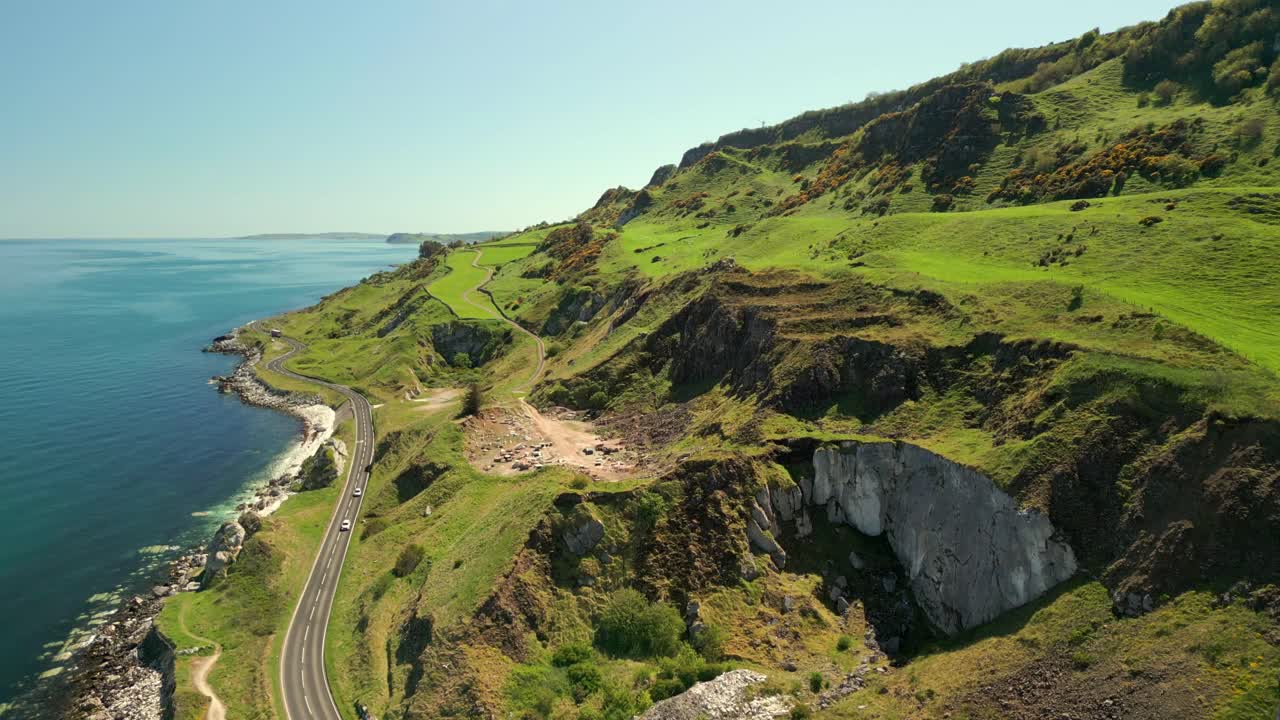 Ultra-wide, advancing aerial video of the Causeway Coastal Route in County Antrim, Northern Ireland, UK, on a bright and sunny day. Filmed in 4K, 60FPS and with Rec709 color.