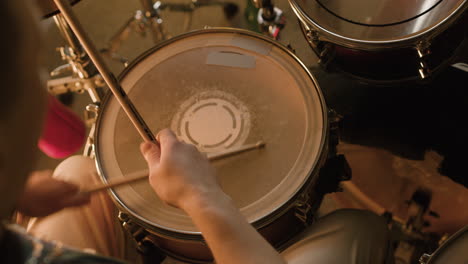 musicista maschio irriconoscibile che suona la batteria durante una prova della band in studio di registrazione 5